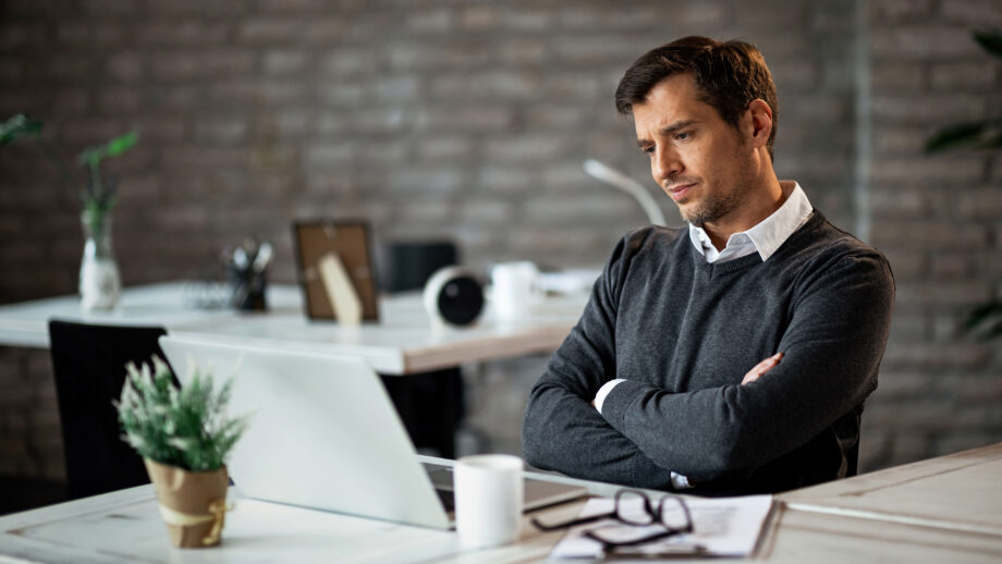 empresario disgustado brazos cruzados leyendo correo electronico computadora portatil trabajo